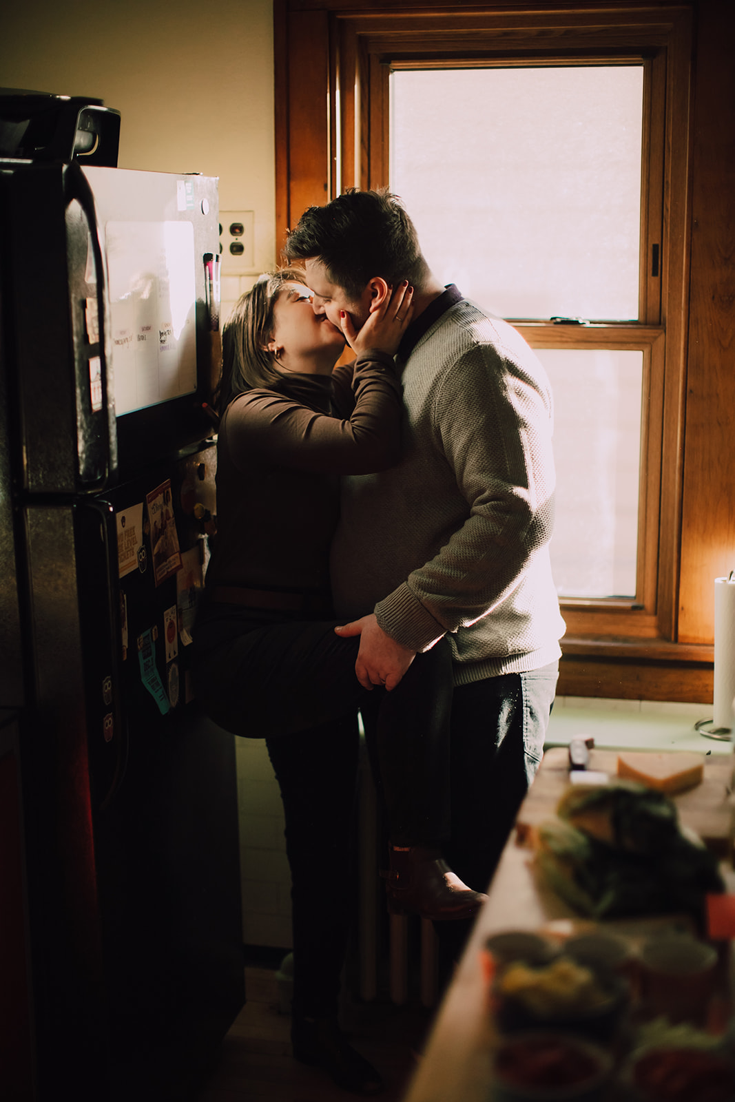 A married couple kisses against the fridge in their home during a couples in-home session in Milwaukee, WI
