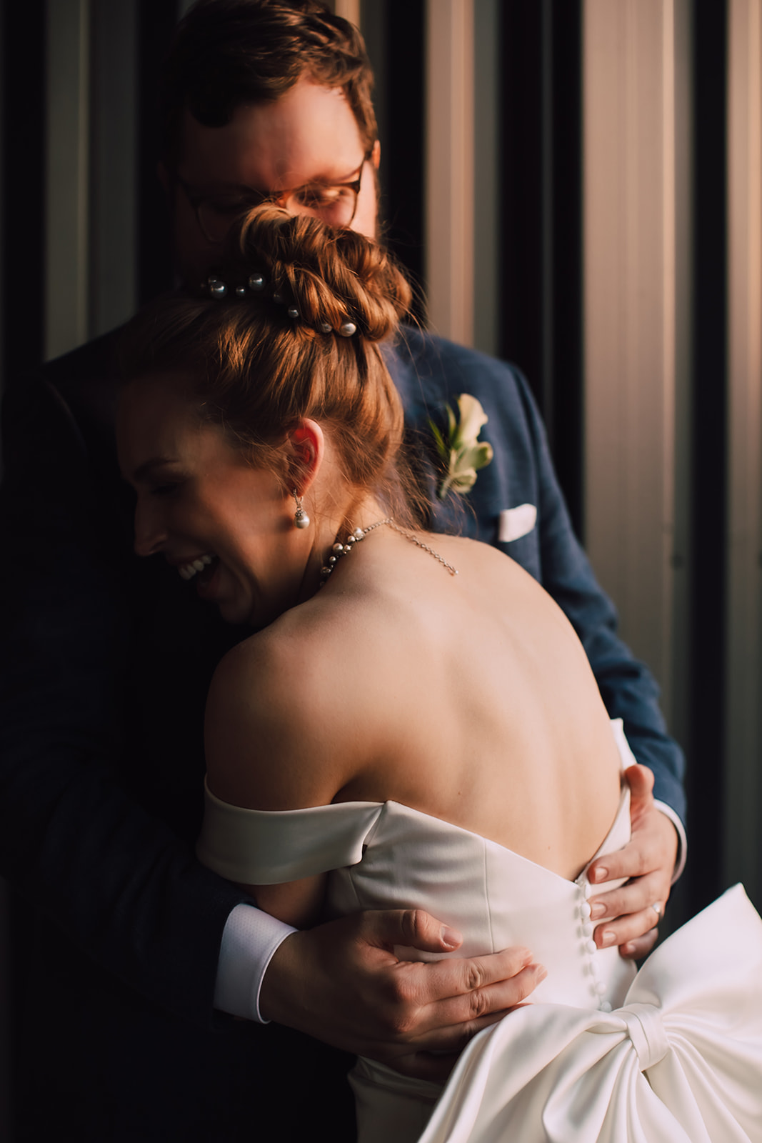 Golden hour light shines, highlighting the back of a bride and part of a groom's face; captured by Milwaukee wedding photographers O & B Photo Co.